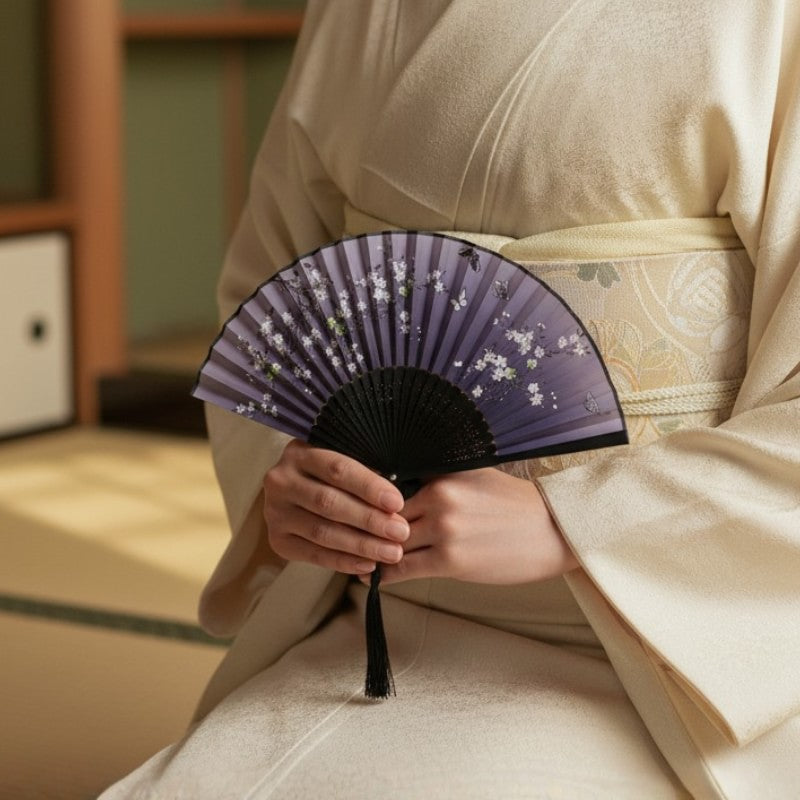 Vintage japanese fan with twilight purple design white blossoms and butterflies held by person in cream kimono in traditional tatami room