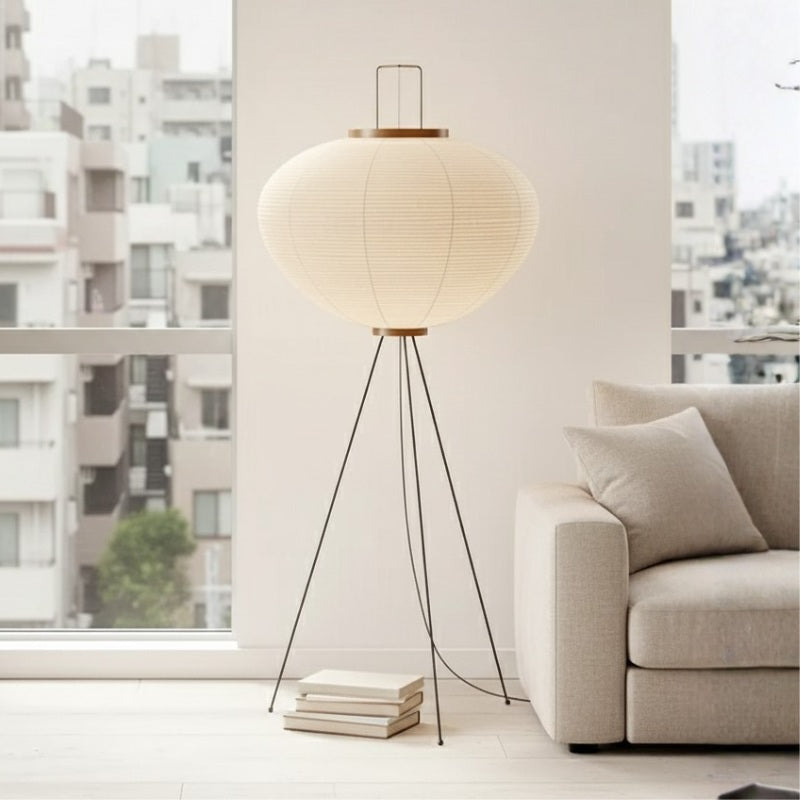 Sculptural wabi-sabi floor lamp with organic elliptical shade standing beside modern sofa near bright urban window