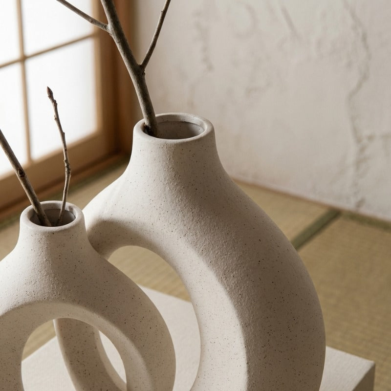Close up of white vintage japanese vase with branches showcasing sculptural circular design near window