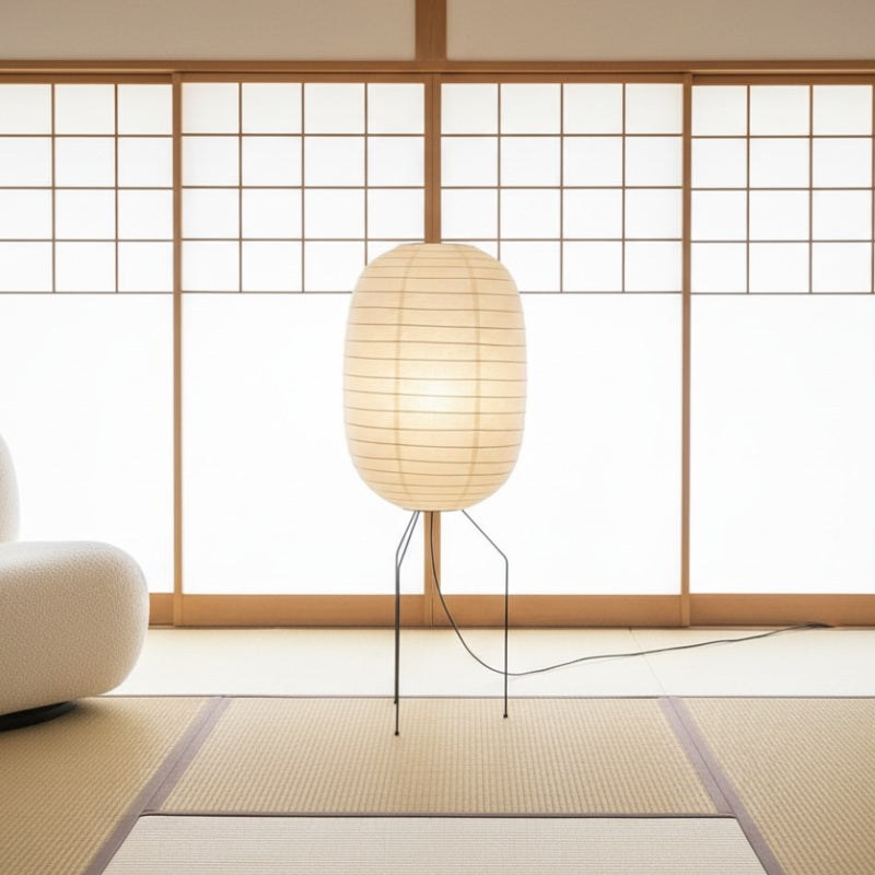 Glowing akari lamp nugochi with organic oval rice paper shade on minimalist wire tripod base in traditional tatami room near shoji window