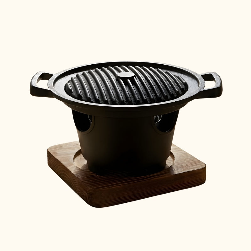 Barbecue Japanese style grill with round ridged cooking surface and black ceramic bowl on natural wood stand