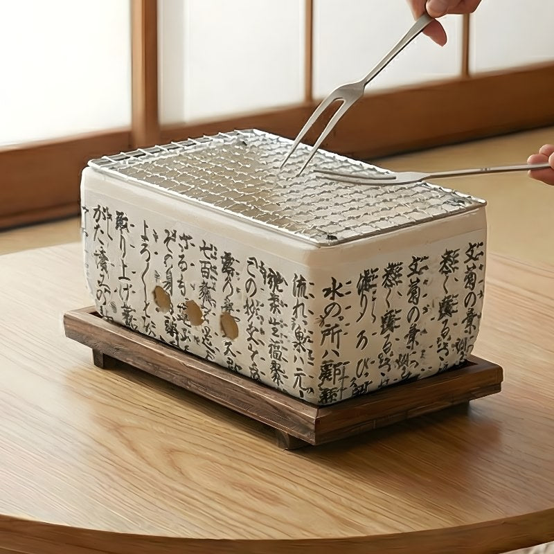 Barbecue Japanese white ceramic cooker with metal tongs grilling on mesh surface with traditional kanji script decoration