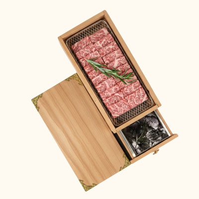 Premium bbq grill wood japanese with marbled wagyu beef slices and charcoal drawer open on white background