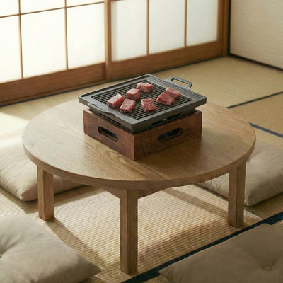 BBQ Japanese grill with cast iron cooking surface and premium beef slices on round wooden table in traditional tatami room