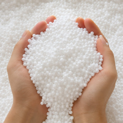 Close-up of white EPS bean bag fillers micro beads cupped in two hands against a soft white bead background