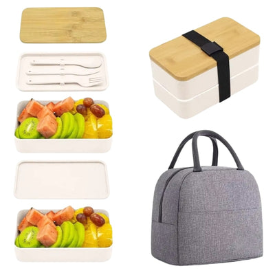 White bento box japanese lunches with bamboo top displaying two-tier design filled with colorful fresh fruit and white utensils beside gray insulated lunch bag