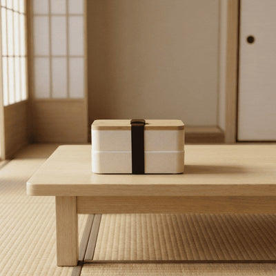 Cream white bento box lunches japanese design with bamboo lid displayed on low wooden table with tatami mat and shoji backdrop