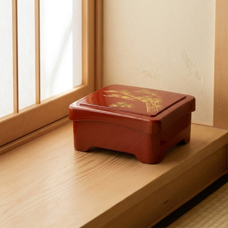 Bento box sushi red with golden pine tree motif on windowsill in traditional Japanese interior with natural light