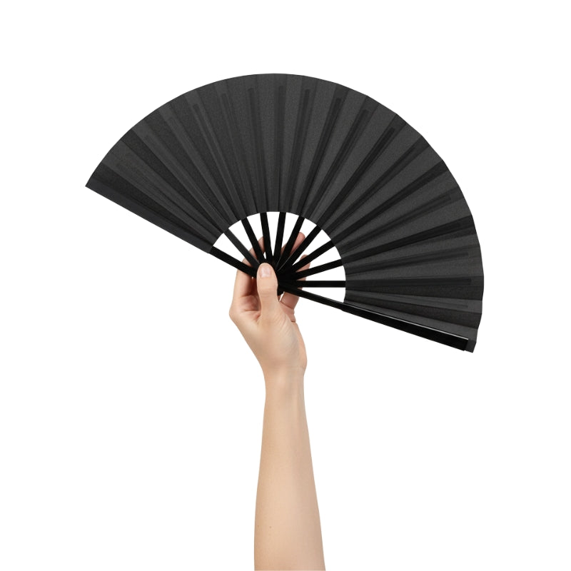 Classic big japanese fan black held gracefully in hand against neutral backdrop highlighting matte finish and traditional structure