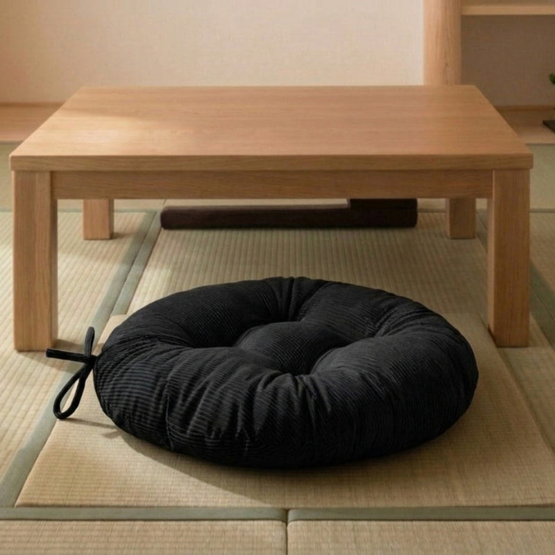 Resting on tatami in front of a low wooden table, this black cushion floor meditation piece has a ribbed corduroy texture