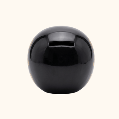 Rear view of a black Japanese Daruma doll with a glossy finish and a narrow coin slot.
