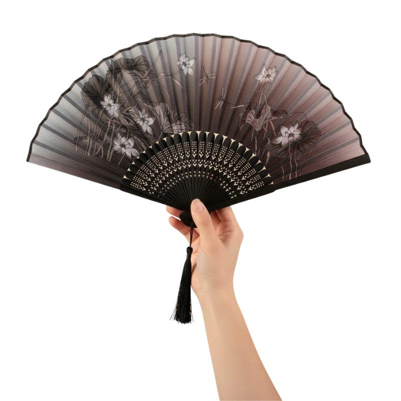 Hand displaying black fan japanese featuring dark to rose gradient with white iris flowers and decorative carved bamboo frame