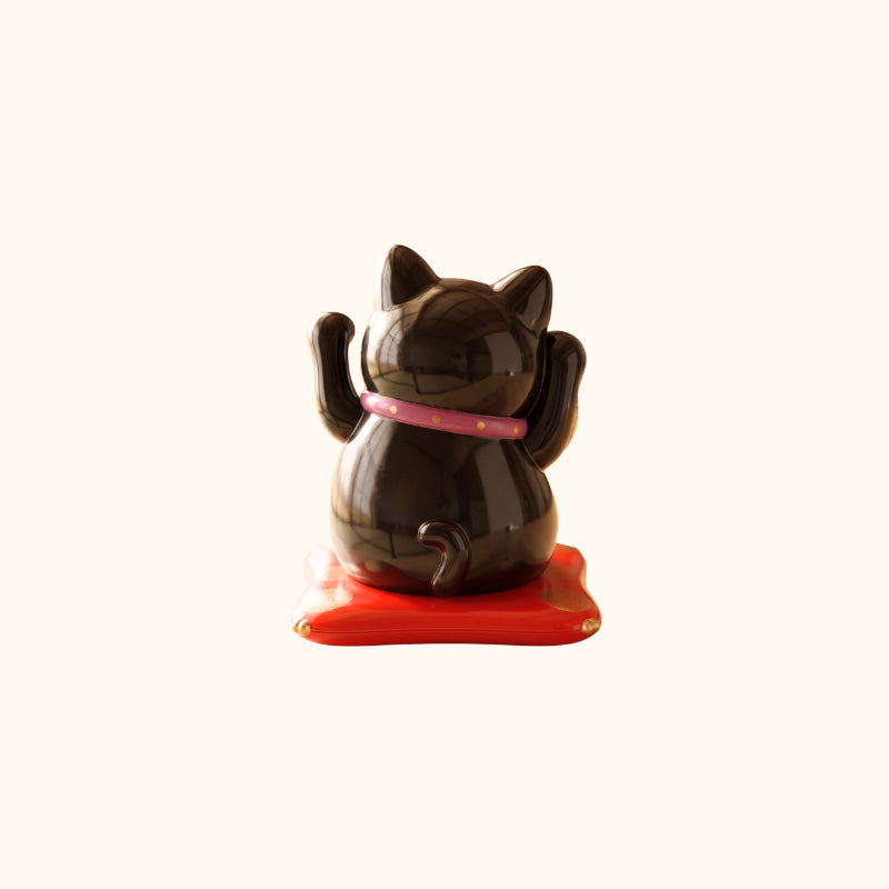 Black Maneki Neko Cat Japanese lucky cat figurine, rear view with raised paws, pink collar and red base
