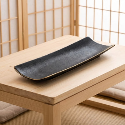 Modern black plate for sushi with matte texture and natural wood rim on minimalist Japanese table