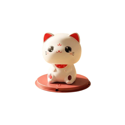 White cat good luck maneki neko with open eyes and red accents sitting on terracotta solar base on clean neutral background