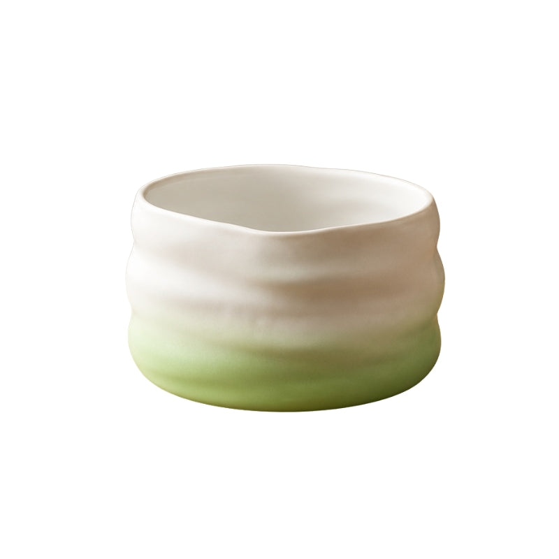 Ceramic matcha bowl in green gradient with wavy organic shape and matte white interior on white background