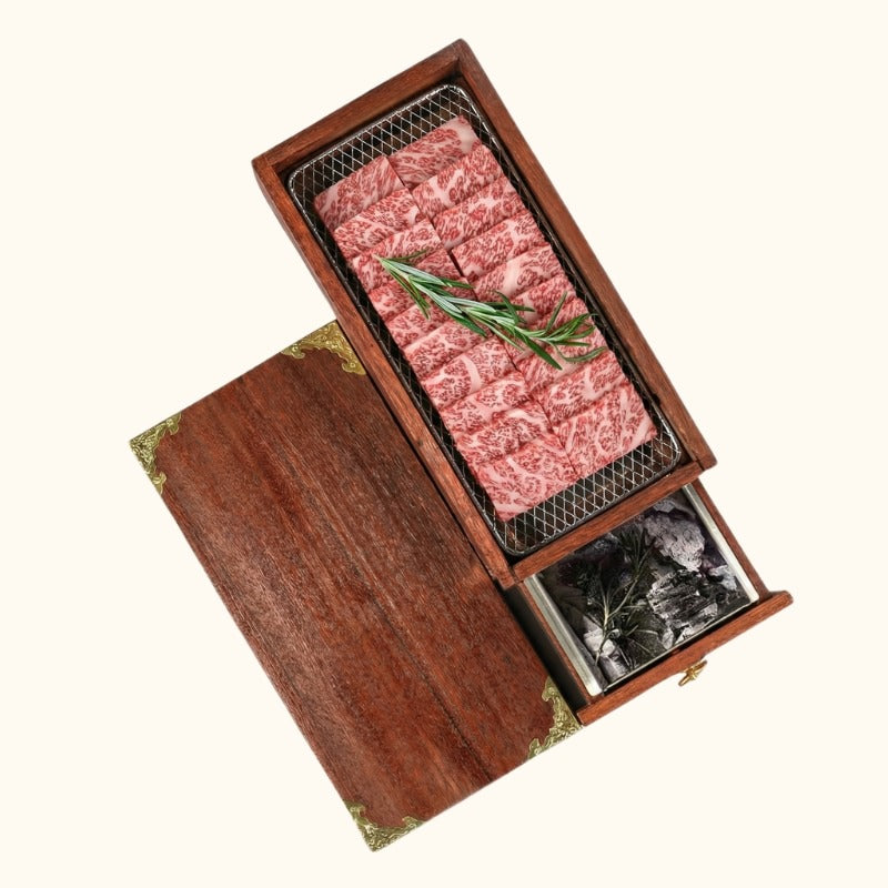 Charcoal barbecue Japanese wood box with marbled wagyu beef on grill and opened ash drawer showing storage compartment