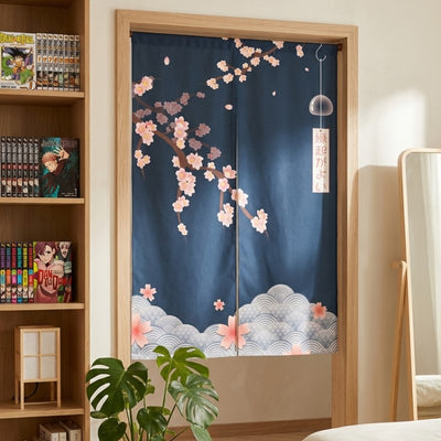 Decorative curtain noren with deep navy sakura blossoms furin wind chime and seigaiha wave border hanging in modern bedroom doorway with manga bookshelf round mirror and monstera plant
