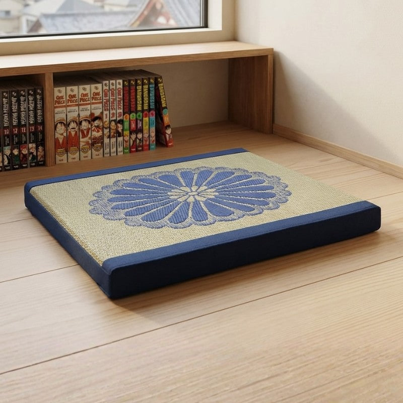 Cushion for meditation with navy blue borders chrysanthemum motif near window with manga bookshelf on wooden flooring