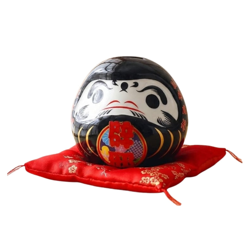 Guardian daruma doll japanese black with vibrant red details displayed on ceremonial red silk cushion against clean white background for clear product view