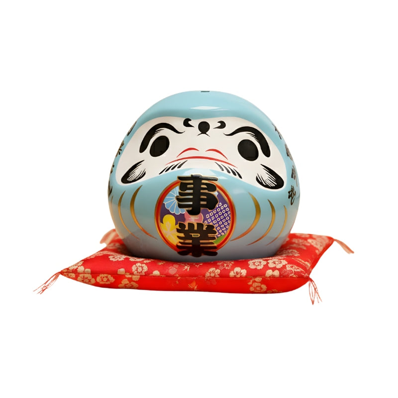 Professional daruma doll japanese blue with colorful kanji belly displayed on red floral cushion against clean cream background for clear detailed view