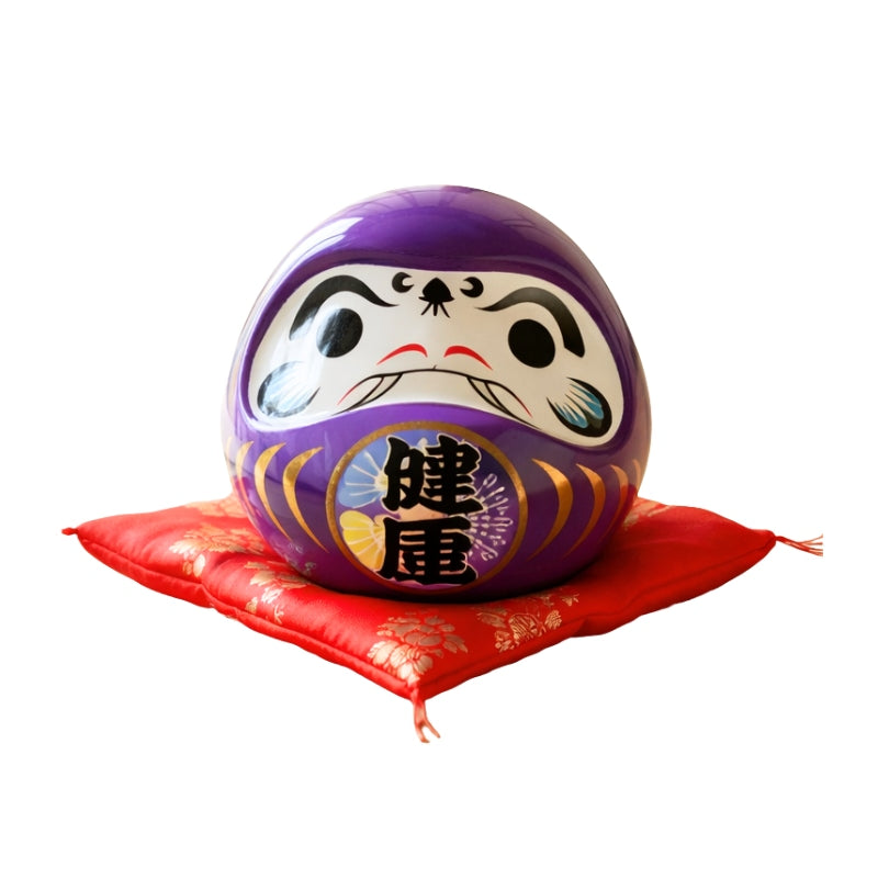 Health symbol kanji on daruma japanese doll purple in rich purple finish with traditional calligraphy displayed on red floral cushion against clean white backdrop