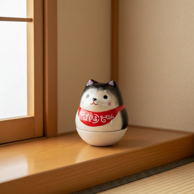 Gray daruma shiba japanese with red fortune collar on wooden windowsill in minimalist Japanese interior