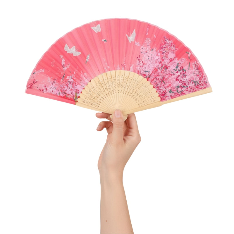Hand elegantly holding fan hand japanese flowers with pink gradient cherry blossoms white butterflies and natural bamboo frame against white background