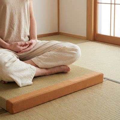 Floor cushion orange japanese with person in white clothing sitting seiza position on tatami mat with shoji screen backdrop