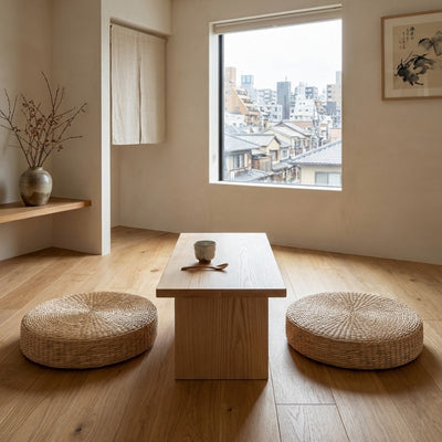 Floor japanese cushion round pair in natural woven rattan beside wooden table overlooking urban rooftops with noren curtain