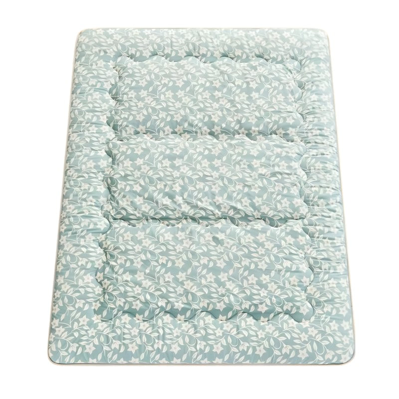 Quilted floor japanese futon mattress with sage green botanical leaf pattern and visible stitching on neutral background