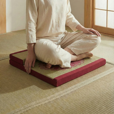 Floor meditation cushion with person in white clothing sitting seiza position on tatami mat with shoji screen backdrop