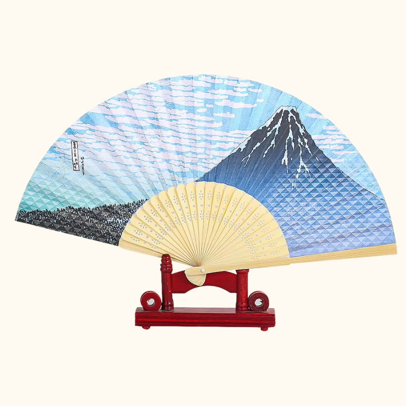 Classic folding fan japanese traditional featuring Mount Fuji blue wave pattern displayed on red wooden stand with natural bamboo frame