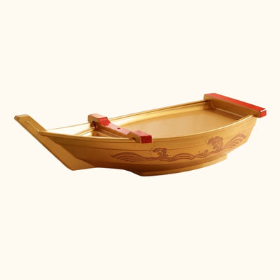 Gold boat sushi curved serving platter with decorative ocean waves and red compartment dividers on clean background