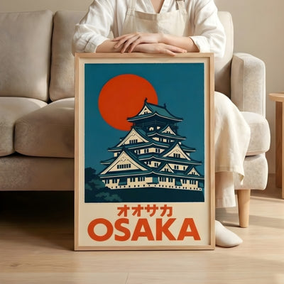 Traditional japanese art prints poster featuring Osaka castle and red sun held by person in minimalist living room with beige sofa