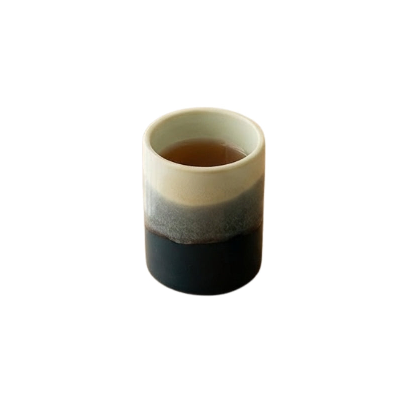 Ceramic japanese tea cup long with ocean gradient glaze from ivory to deep blue filled with tea on white background