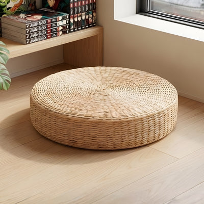 Japanese cushion floor in natural woven rattan near window with manga collection and monstera plant on wooden flooring