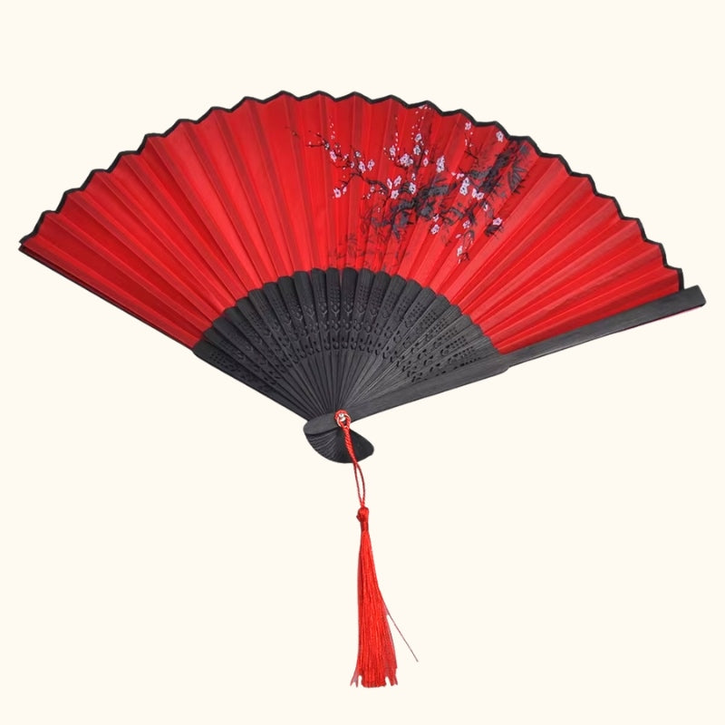 Traditional japanese dance fan fully opened displaying crimson paper surface with plum blossom artwork and carved black bamboo frame on white background