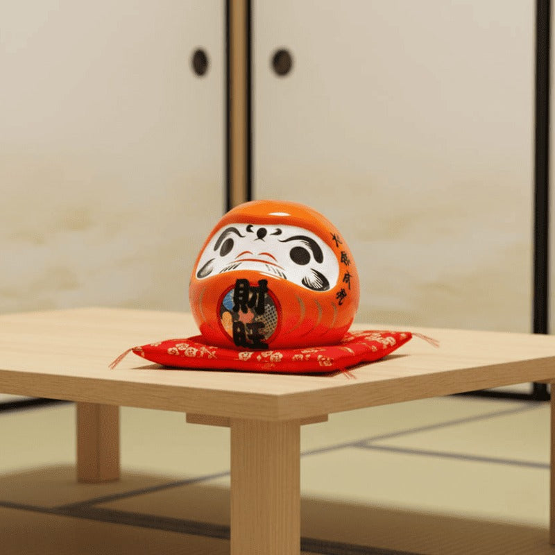 Traditional japanese daruma ceramic in warm orange tones with kanji calligraphy placed on red cushion atop low wooden table in minimalist tatami room space