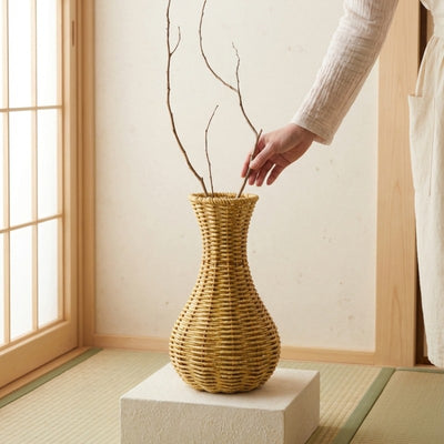 Japanese flower vase hand woven from natural fibers, styled with branches in a traditional Japanese interior.