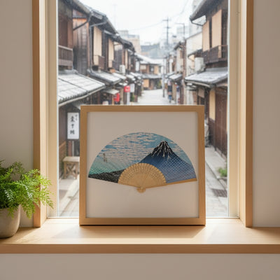 Authentic japanese folding fan traditional with Mount Fuji landscape displayed in wooden frame on window sill overlooking historic snowy Kyoto street