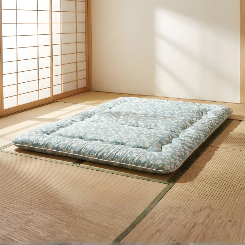 Japanese futon floor mattress with leaf pattern on tatami near shoji screen in minimalist room with natural sunlight