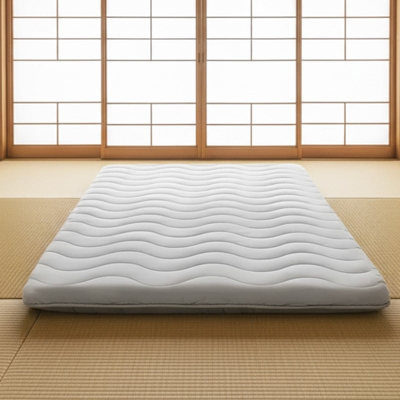 Classic japanese futon with wave quilting pattern positioned on traditional tatami mat floor near bright shoji screens in serene interior