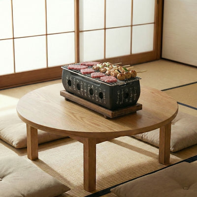 Japanese grill barbecue cooking marinated beef and yakitori skewers on round wooden table in authentic tatami mat room with floor cushions