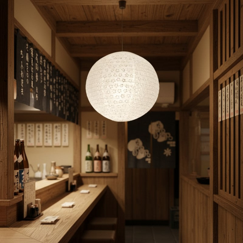 Illuminated japanese hanging lantern creating warm ambient glow in authentic izakaya interior with wooden counter and sake bottles