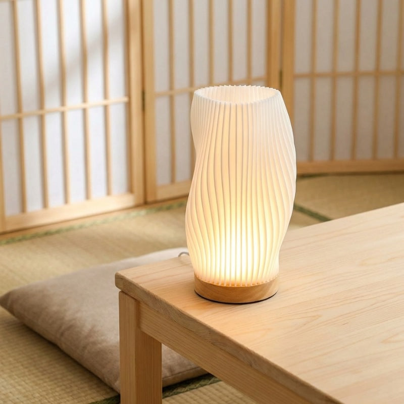 Japanese lamp modern white pleated paper shade with twisted waist shape on wooden base glowing on low table in tatami room
