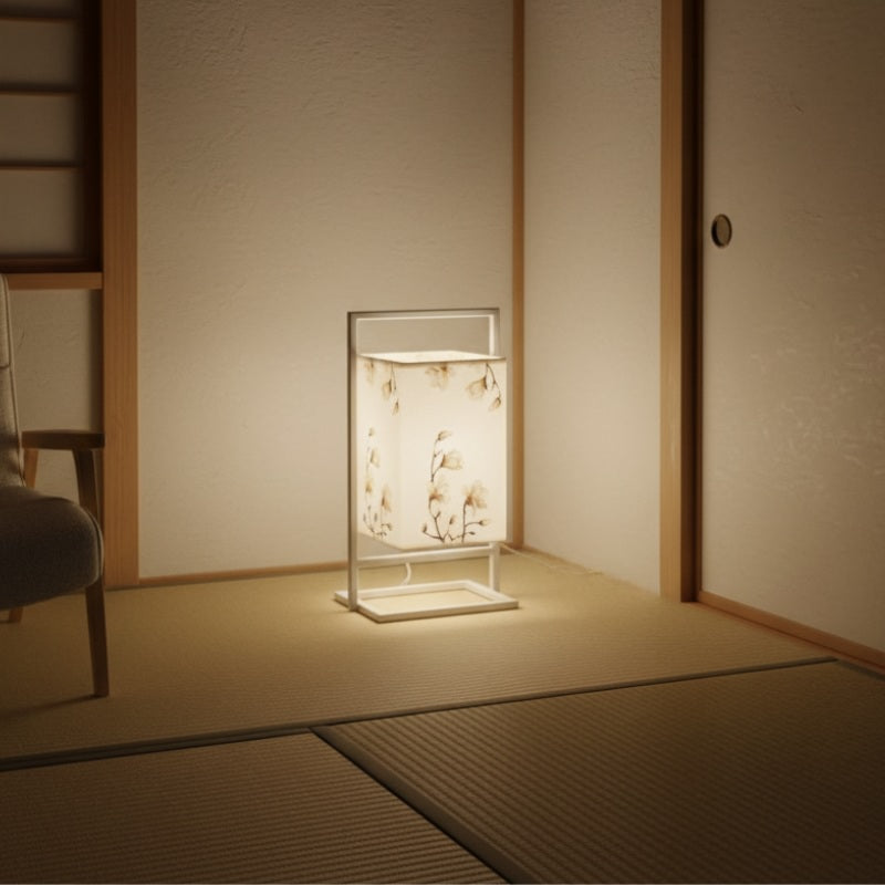 Elegant japanese modern table lamp with beige cotton flowers on white fabric shade and aluminum frame glowing softly in traditional tatami room