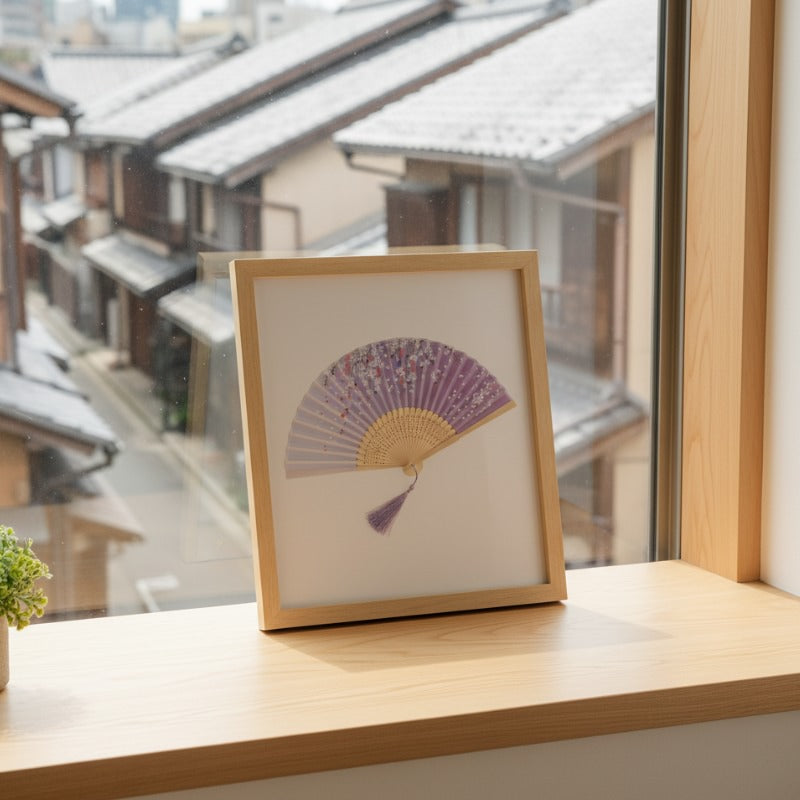 Framed japanese paper folding fan purple with scattered cherry blossoms displayed on wooden windowsill overlooking snowy traditional Japanese street