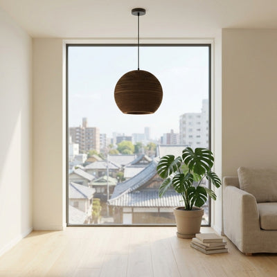 Japanese pendant light style spherical shade in dark brown corrugated cardboard hanging in contemporary room with city views