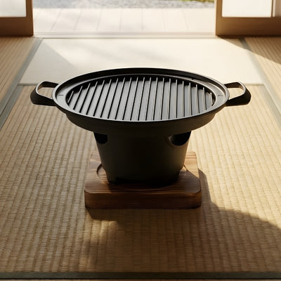 Japanese style barbecue plate with round ridged cooking surface on natural wood platform near zen garden view through shoji doors